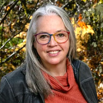 Bernice Freed Bravo, smiling, in front of autumn leaves